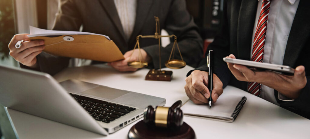 two lawyers with paperwork and a laptop