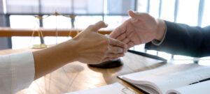 people shaking hands in front of a Scale of Justice