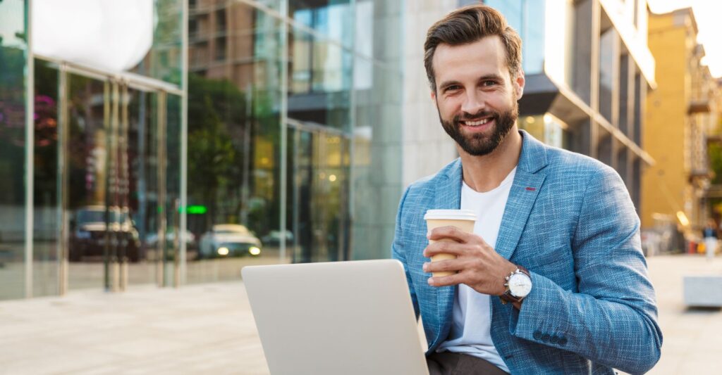 Business man sitting outside with a coffee and laptop