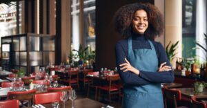 Female restaurant owner standing beside tables