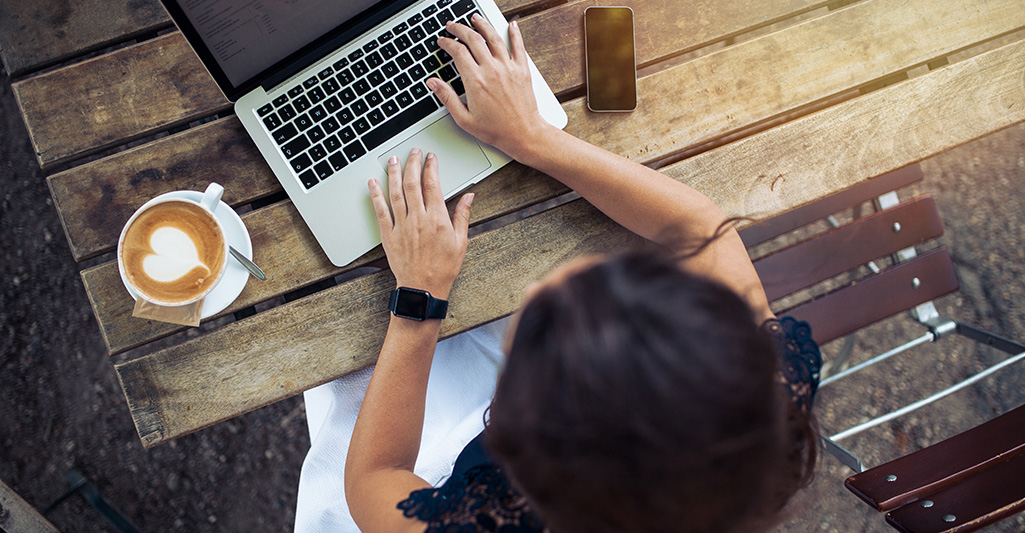 Top view of a woman on her laptop at a bench outside
