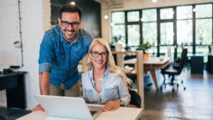 Two people smiling while working at a laptop