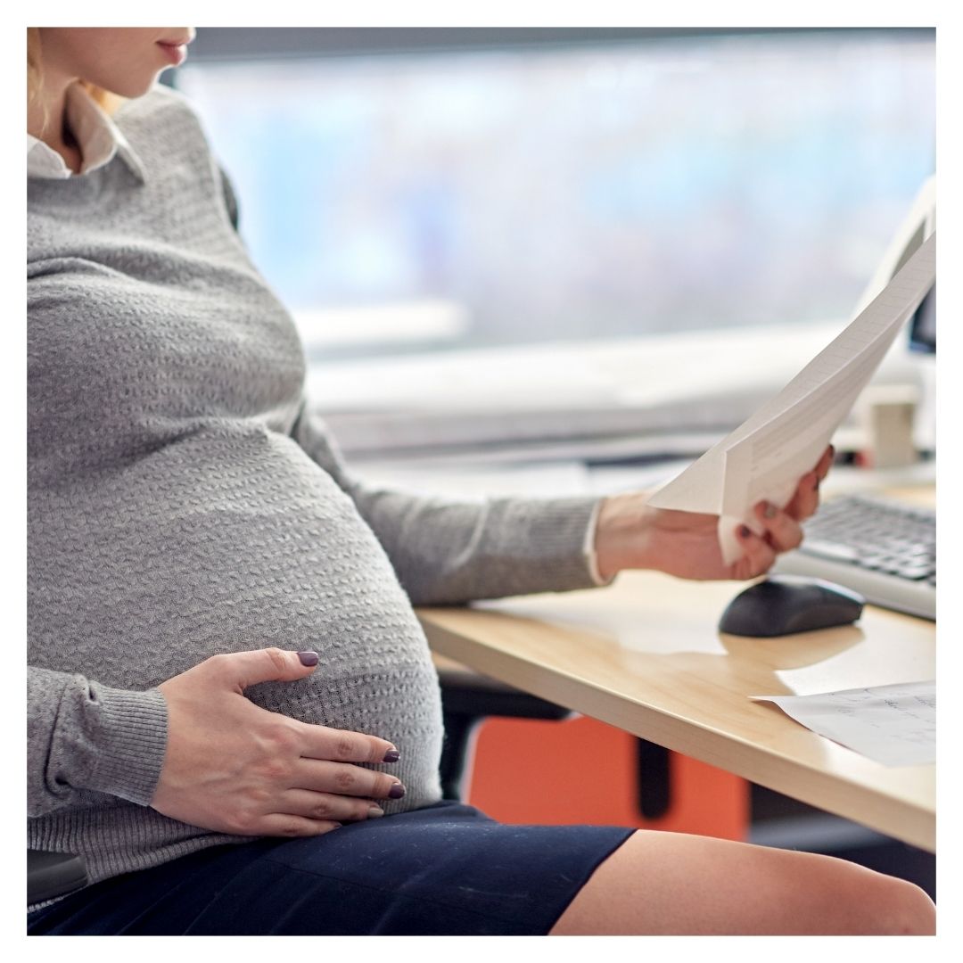 Pregnant employee sitting and reading document