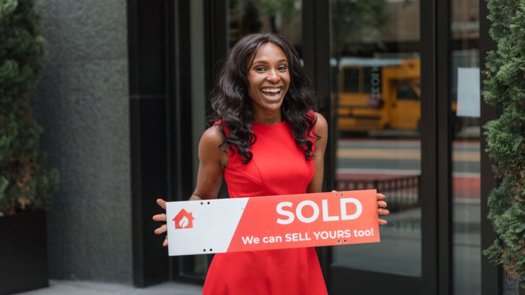 a woman holding a sold sign