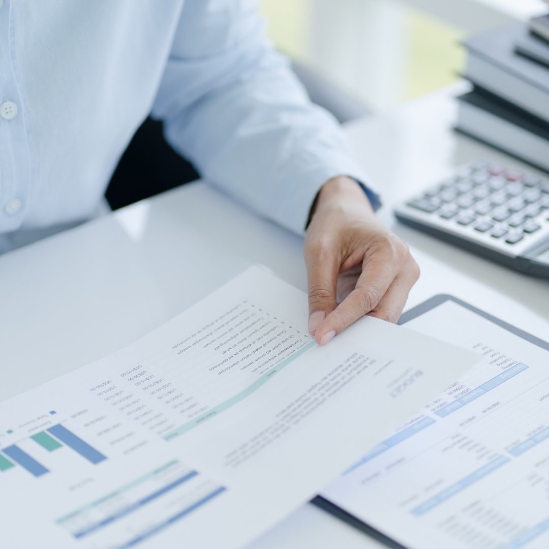 person in button down shirt holds document on desk