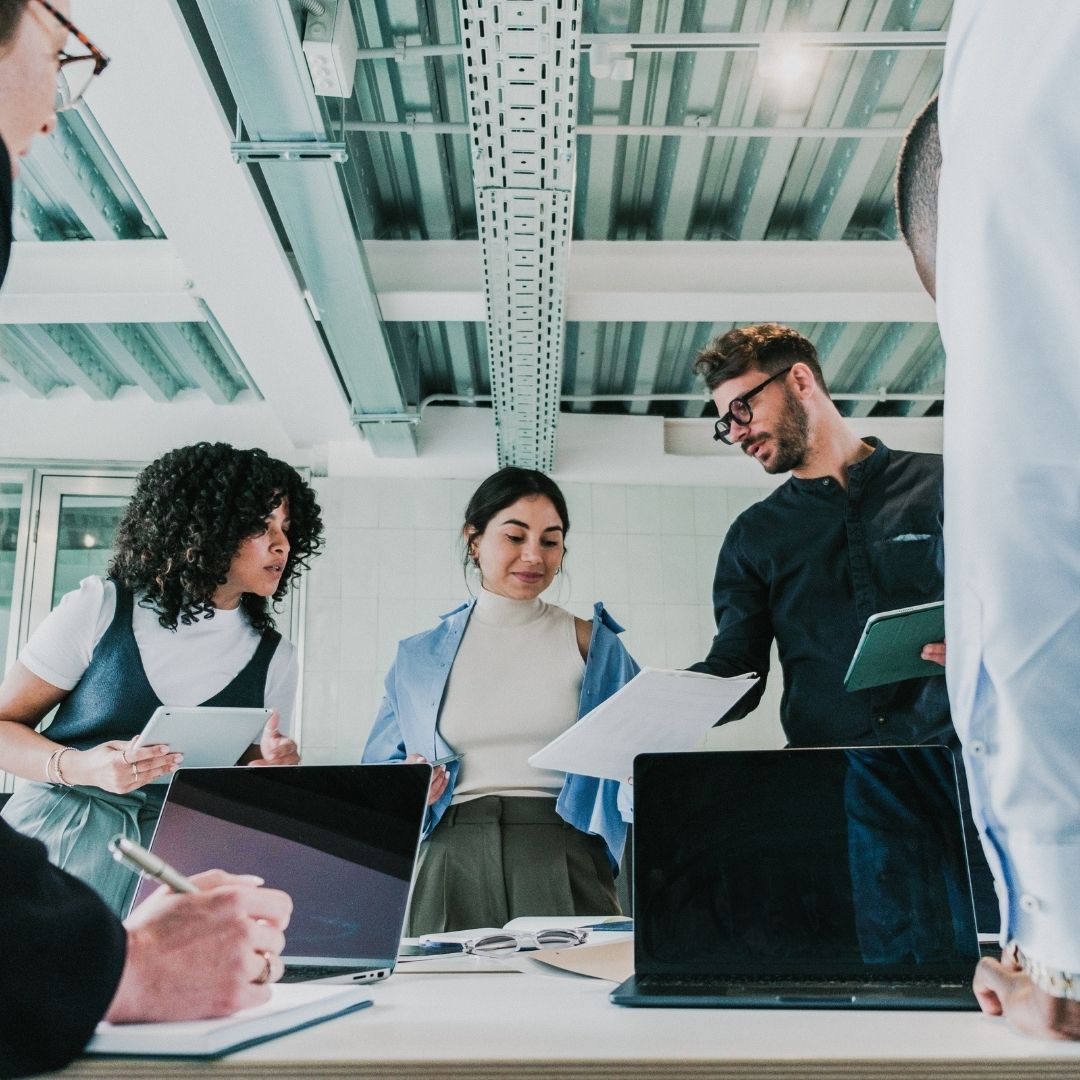 employees stand around conference table