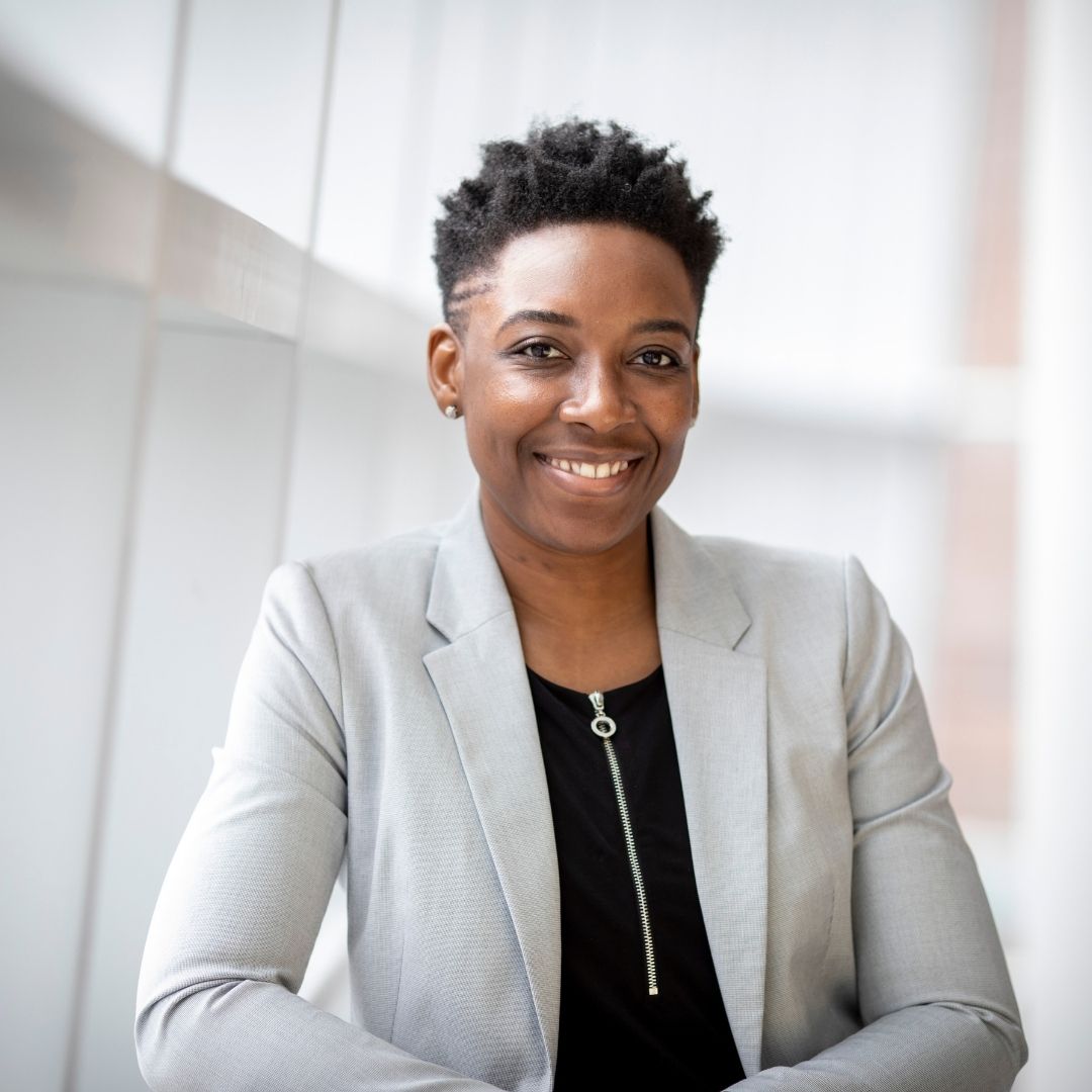 woman in blazer leans against railing