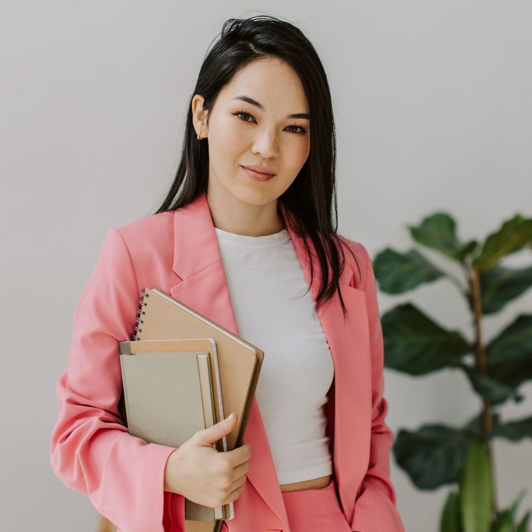 woman in pink suit holds notebooks