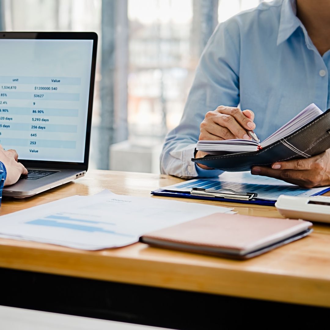 people sitting at desk with documents and laptop