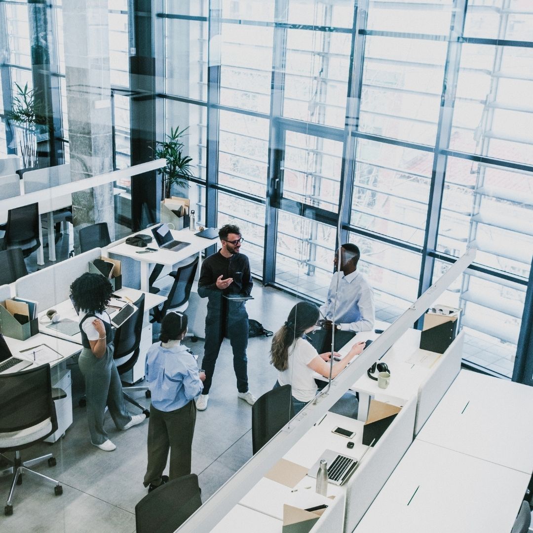 people stand in aisle between desks in office