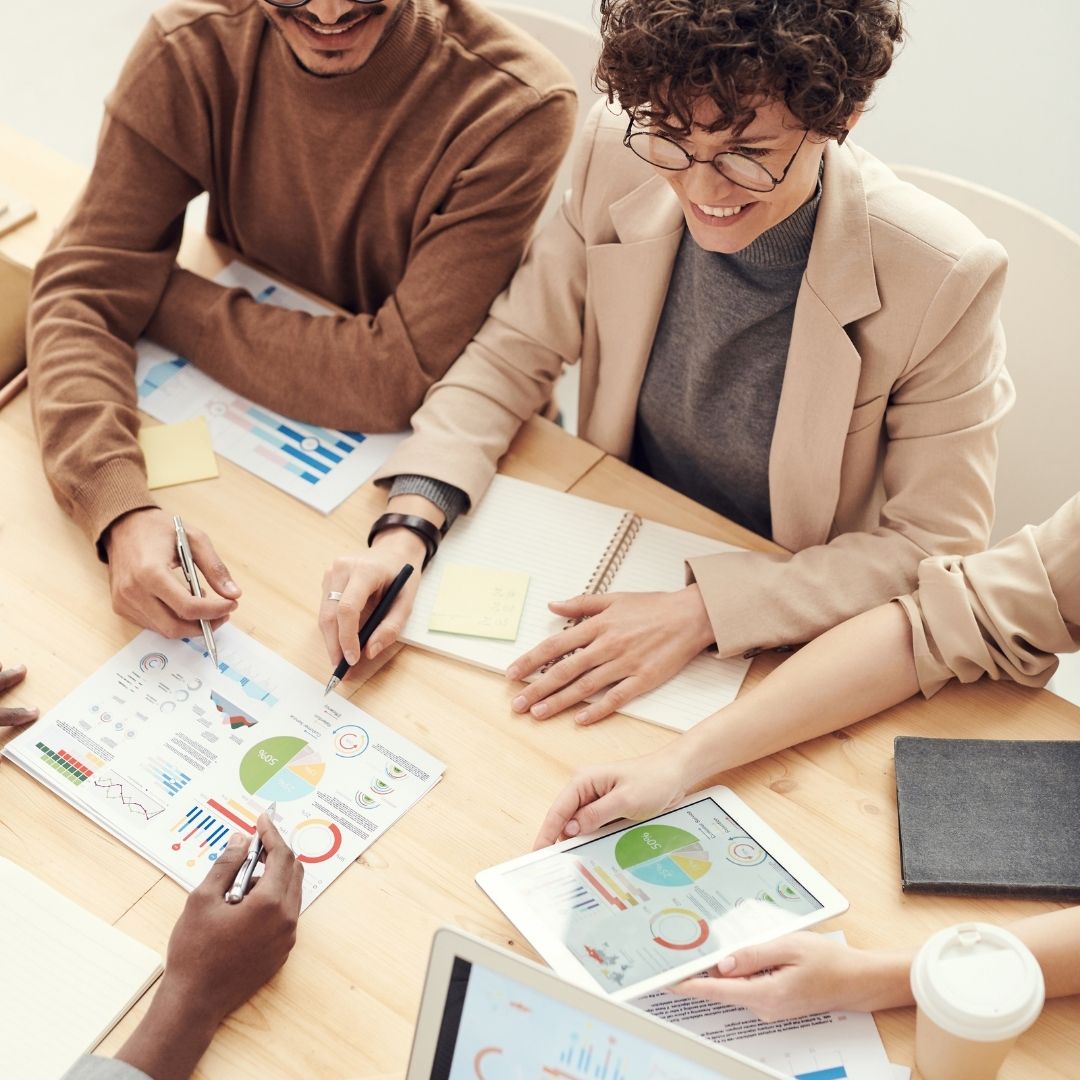 people sit at table with printed charts and graphs